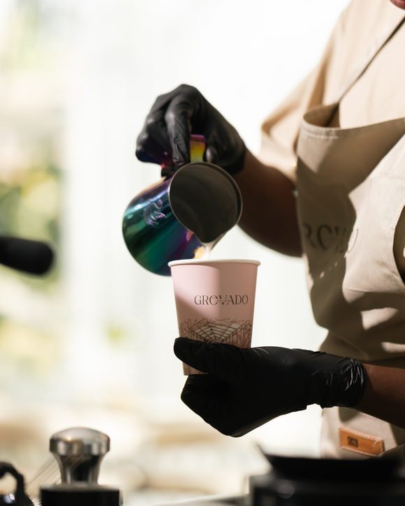 A barista pouring a coffee at the Grovado counter