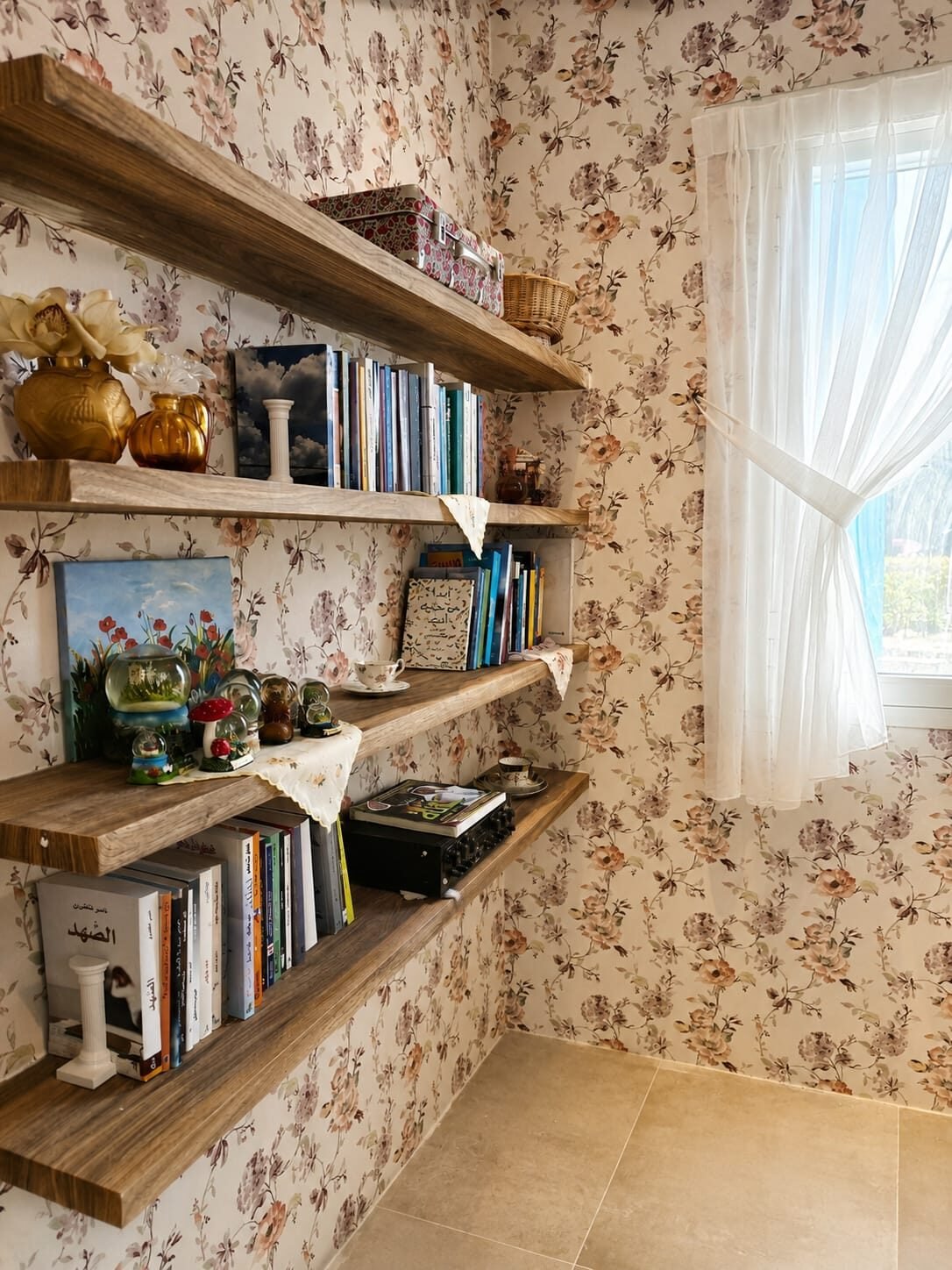 A floral-papered reading nook at Grovado, with shelves of books, teacups and snow globes